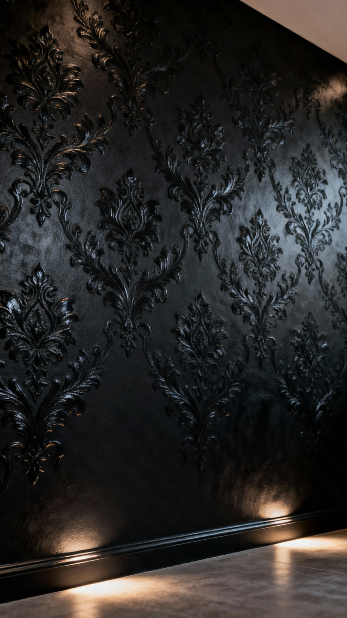 Close-up of a luxurious black bedroom wall featuring subtle tonal and embossed damask patterns, highlighted by elegant uplighting to reveal intricate texture and depth.