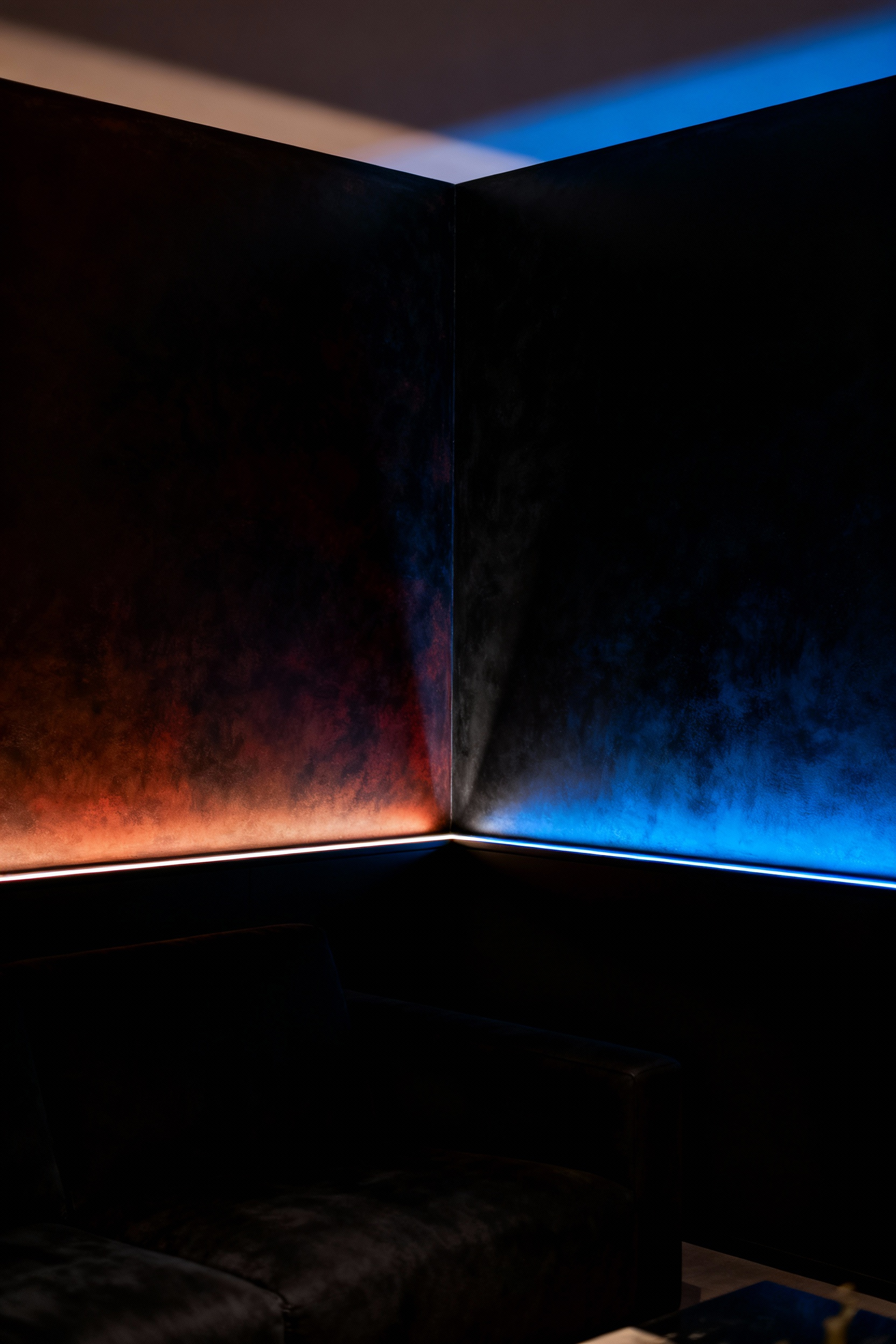 Luxurious living room corner showcasing two distinct black paint undertones (warm brown-black and cool blue-black) under sophisticated lighting, illustrating the impact of pigment nuances in interior design.