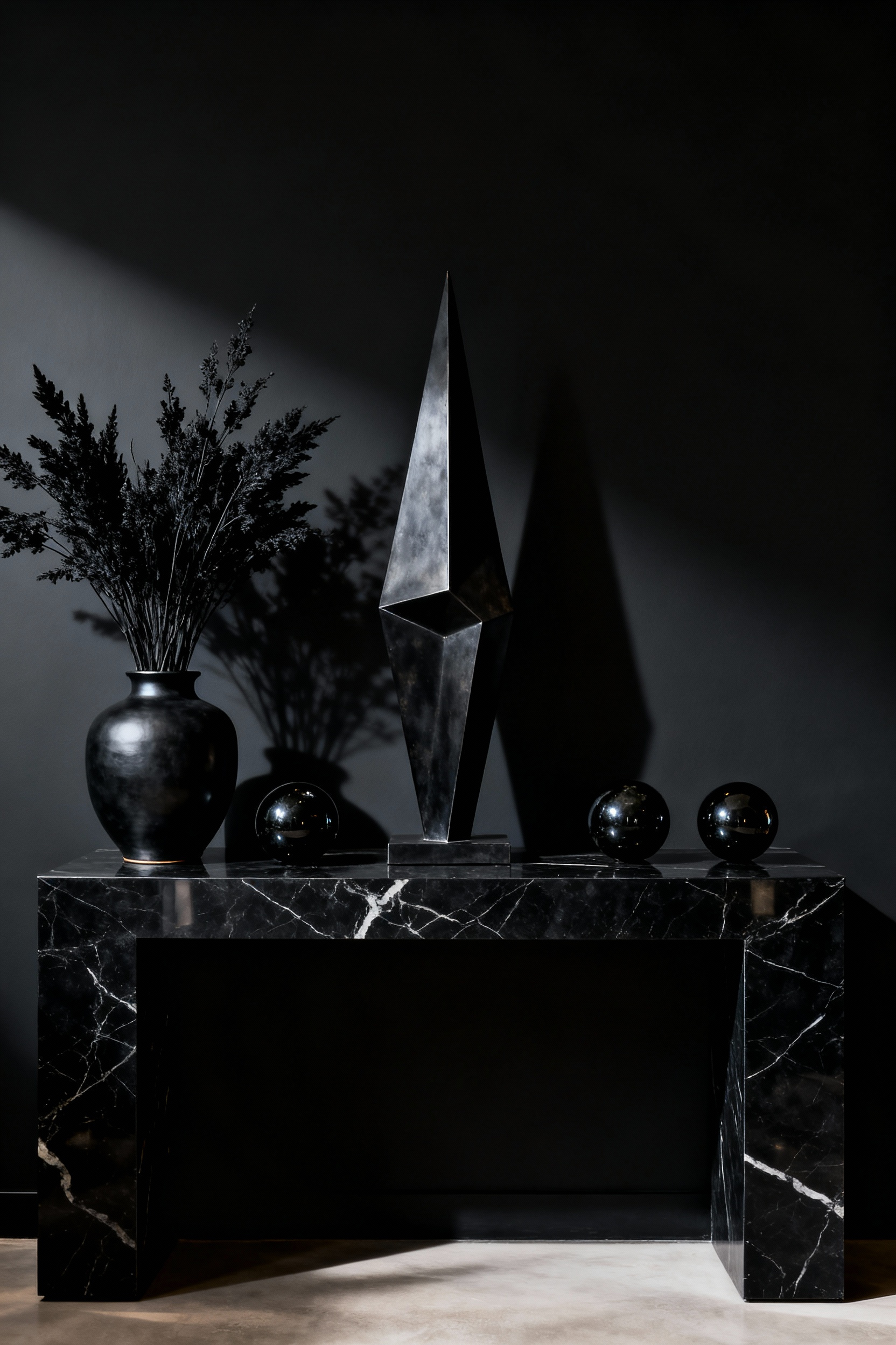 A meticulously arranged dark living room vignette with varied textures and dramatic chiaroscuro lighting on a black marble console table.