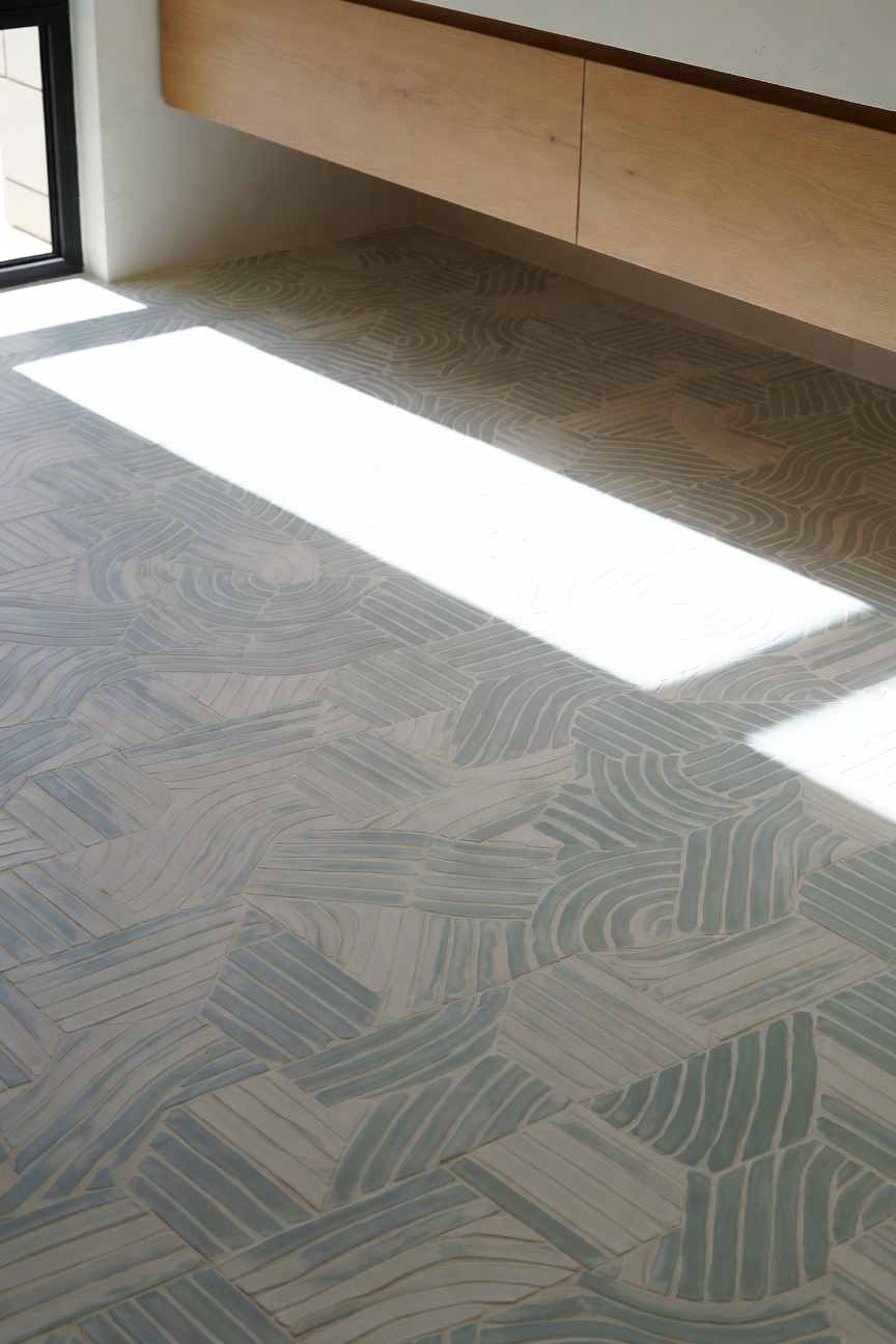 Matte encaustic cement bathroom floor tiles in ocean mist blue and sandy beige, featuring a breezy geometric pattern in a contemporary coastal cottage setting